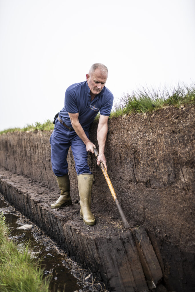 Derek traditionally hand-cutting local peat to smoke the barley to make our Islay Single Malt Scotch Whisky