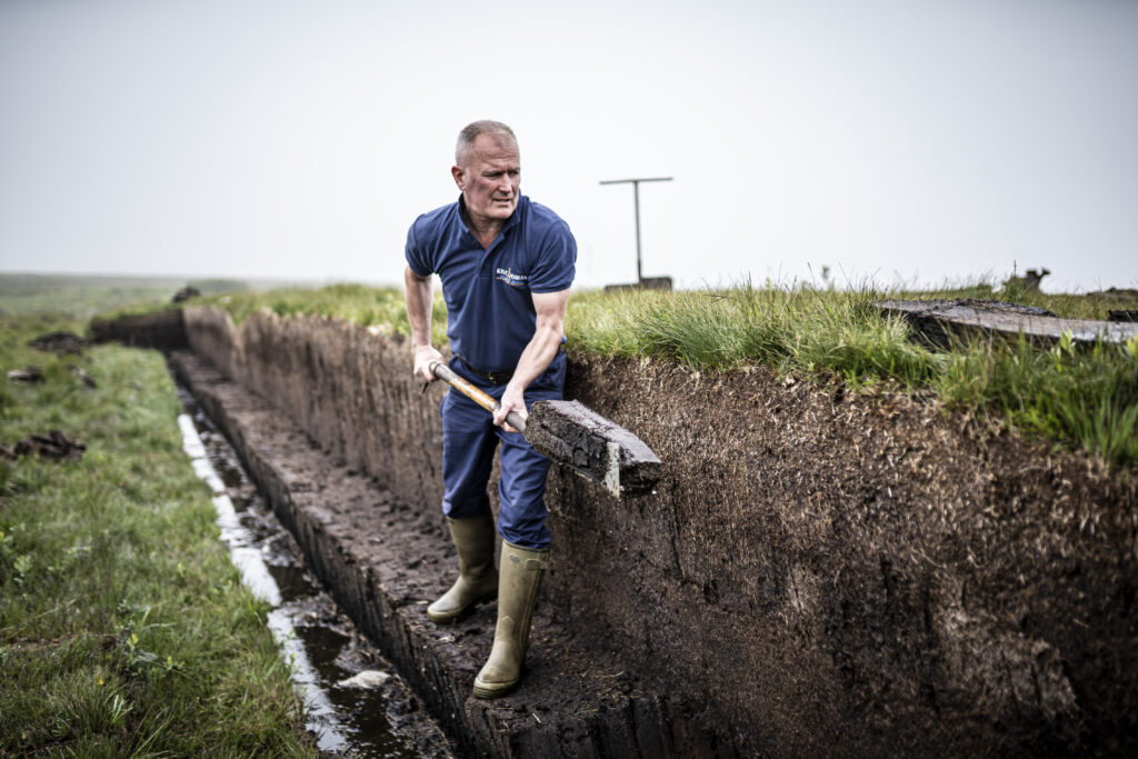 Hand cutting peat on Islay to produce our smoky peated Kilchoman Islay single malt