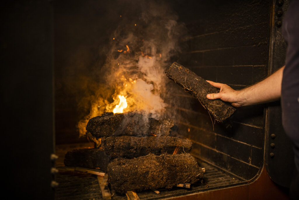 Traditional malt floor at Kilchoman Distillery. Traditional floor malting peated islay whisky. Putting hand cut peat on the kiln fire to smoke the barley to produce a smoky peated Islay whisky